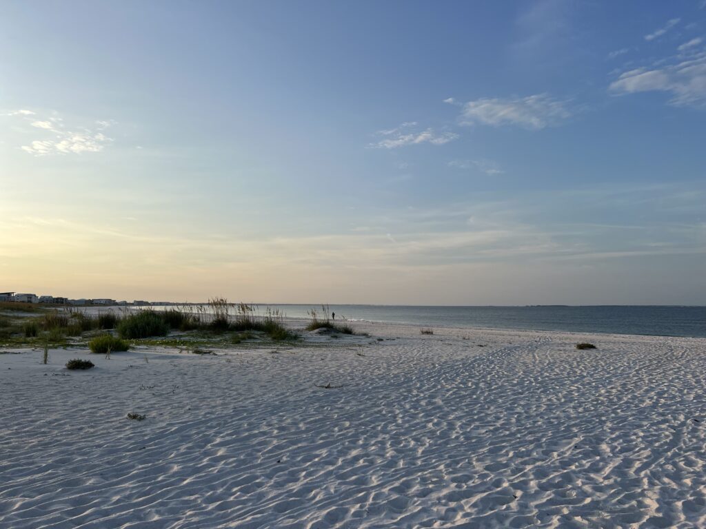 The beach at sunrise in Mexico Beach, Florida, with soft white sand and the ocean in the distance
