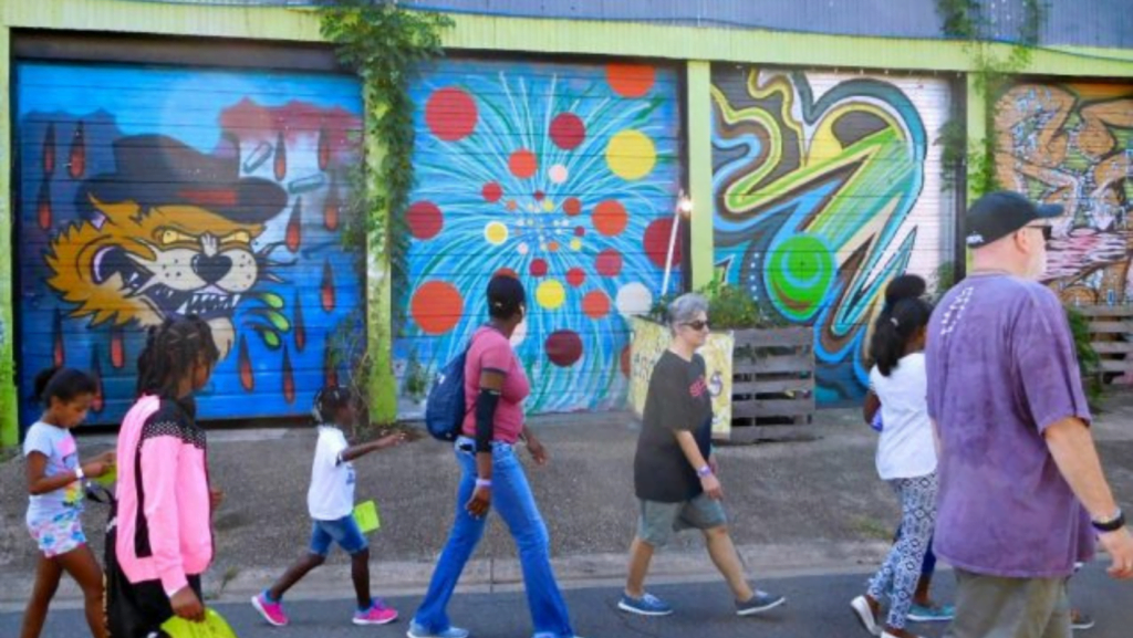 Image of people walking past wall art looking to their left as they walk by. 